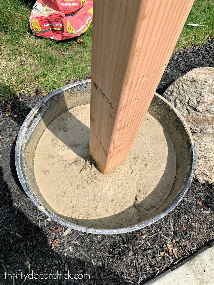 a wooden post sticking out of the ground next to a cement bowl in front of a fire hydrant