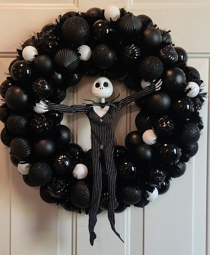 a wreath decorated with black and white balloons is hanging on the front door to celebrate halloween