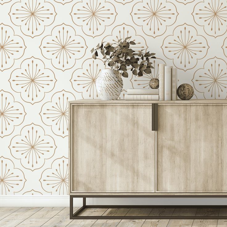 a sideboard with a vase and books on it in front of a wallpapered background