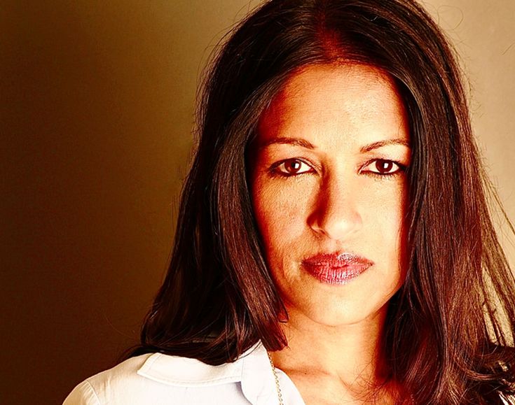 a woman with brown hair and white shirt looking at the camera while posing for a photo