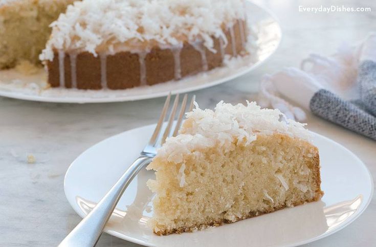 a slice of coconut cake on a plate with a fork next to the rest of the cake