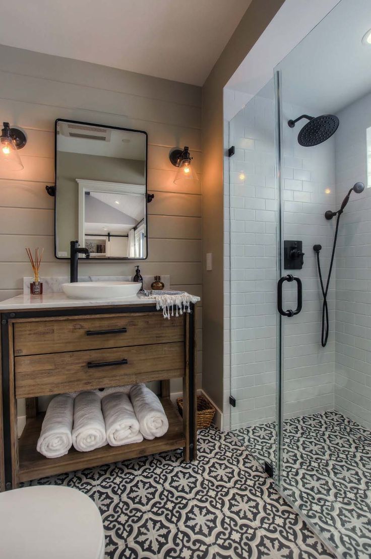 a bathroom with a sink, toilet and shower stall in the middle of it that has black and white tiles on the floor