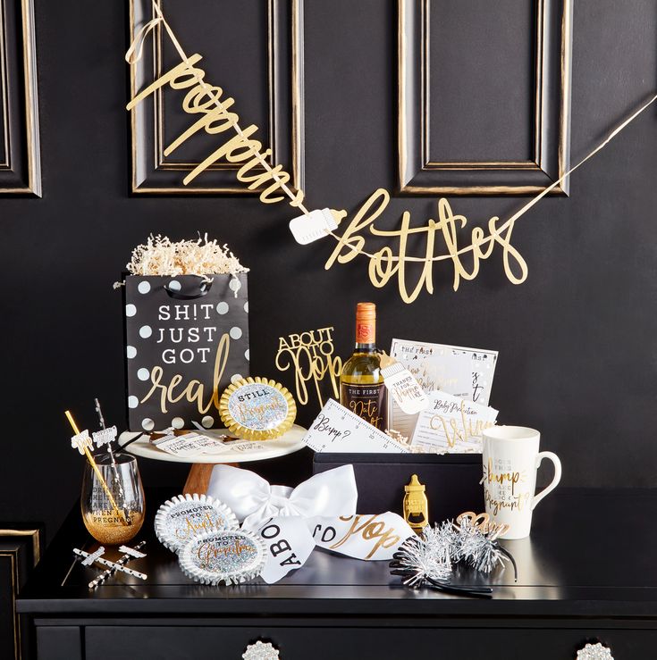 a black and gold birthday party table with champagne, confetti, decorations, and gifts