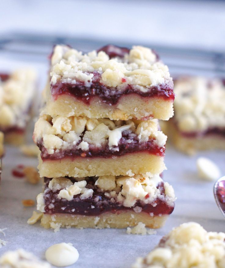 three dessert bars stacked on top of each other with crumbled toppings around them