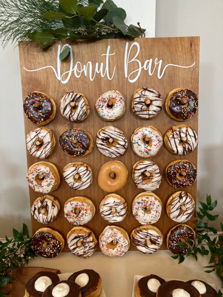 a wooden sign with donuts on it next to other doughnuts and toppings