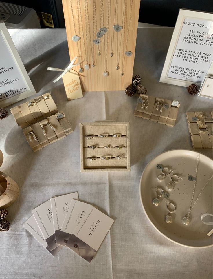 a table topped with lots of wooden boxes filled with jewelry next to cards and pine cones