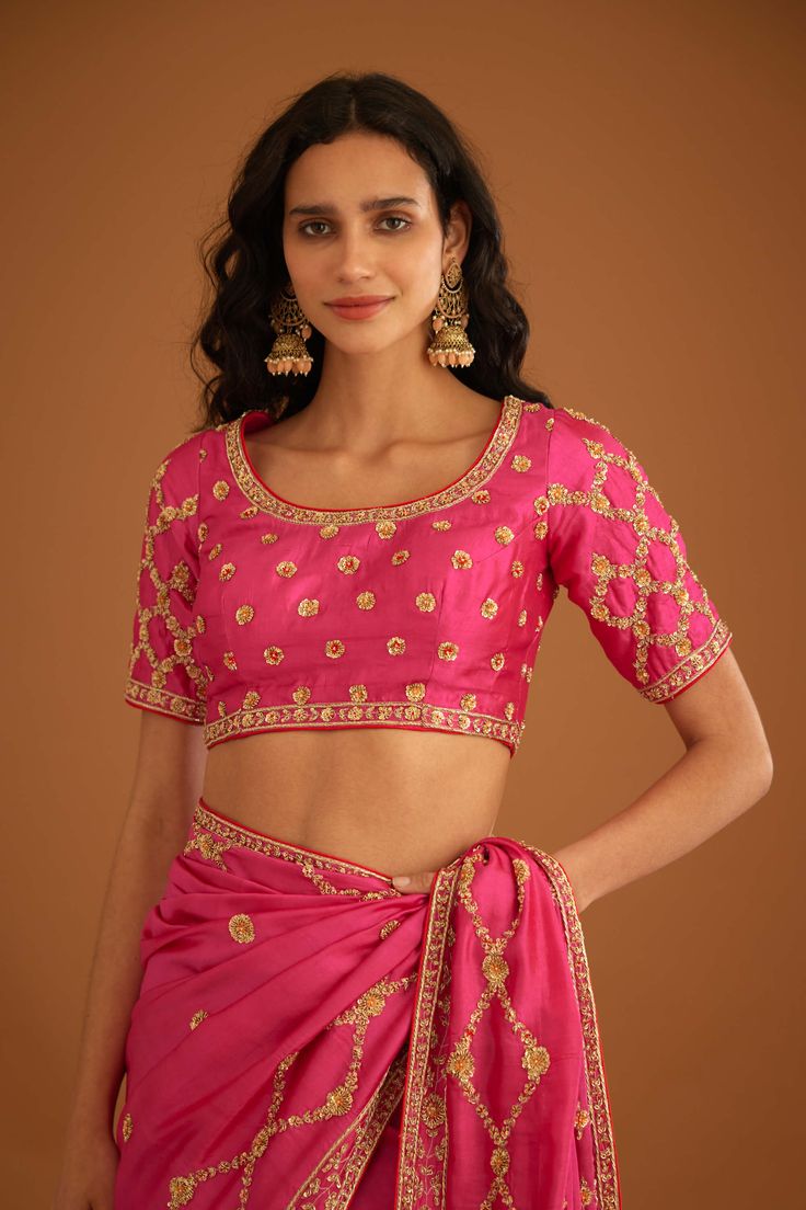 Editor's Note A fuschia pink zardozi embroidered dupion silk sari and blouse would be a stunning and bold choice for a formal occasion. The rich and luxurious fabric of the dupion silk would drape beautifully, while the intricate zardozi embroidery would add texture and depth to the overall look. Color: Pink Fabric: Dupion silk Embroidery details: Zardozi embroidery Components: Sari & blouse Sari length: 6 meters, sari width: 46" inches Occasion: Festive and Wedding Guest Disclaimer: Product col Pink Art Silk Pre-draped Saree With Intricate Embroidery, Pink Raw Silk Pre-draped Saree With Resham Embroidery, Festive Pink Pre-draped Saree With Dori Work, Pink Anarkali Style Silk Pre-draped Saree, Traditional Drape Blouse With Zari Work For Reception, Designer Pink Pre-draped Saree With Zari Work, Pink Silk Pre-draped Saree In Traditional Style, Pink Silk Choli For Parties, Pink Silk Choli For Party