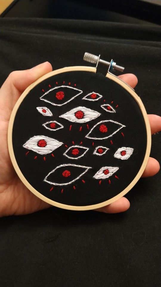 a hand is holding a black and red embroidery