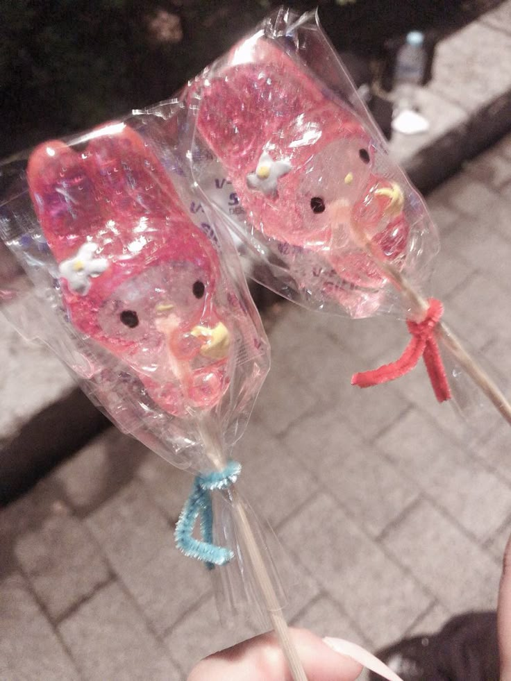 two pink teddy bear lollipops are wrapped in plastic