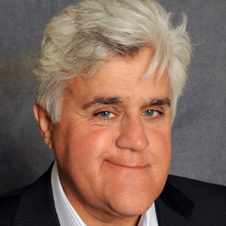 a close up of a person wearing a suit and tie with white hair smiling at the camera