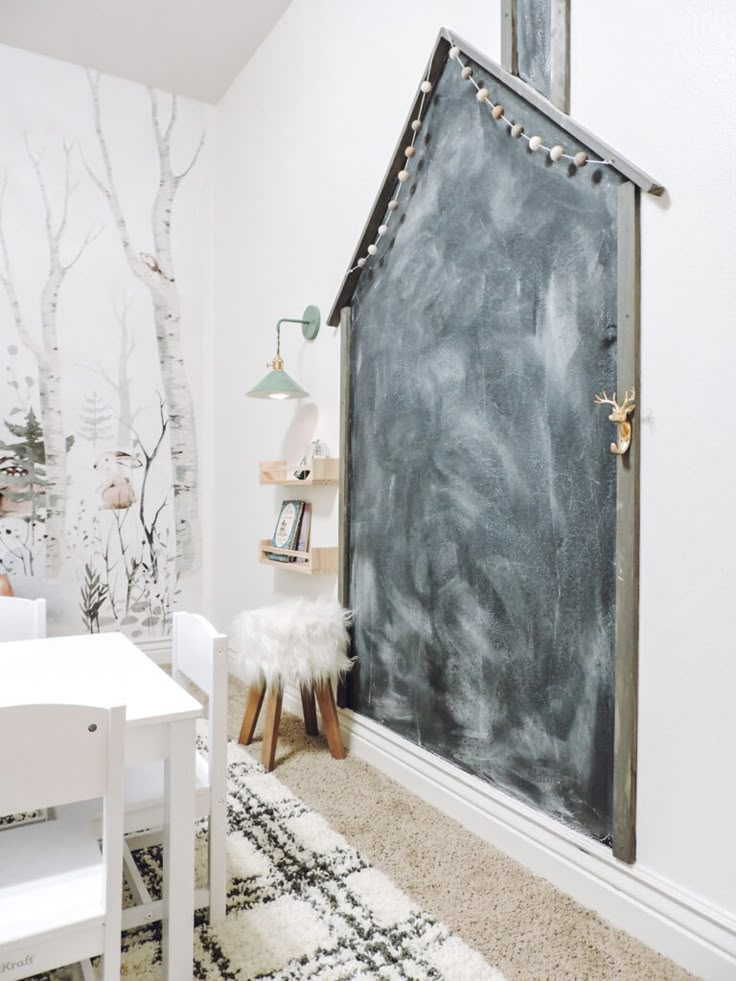 a chalkboard in the corner of a child's room with trees on the wall