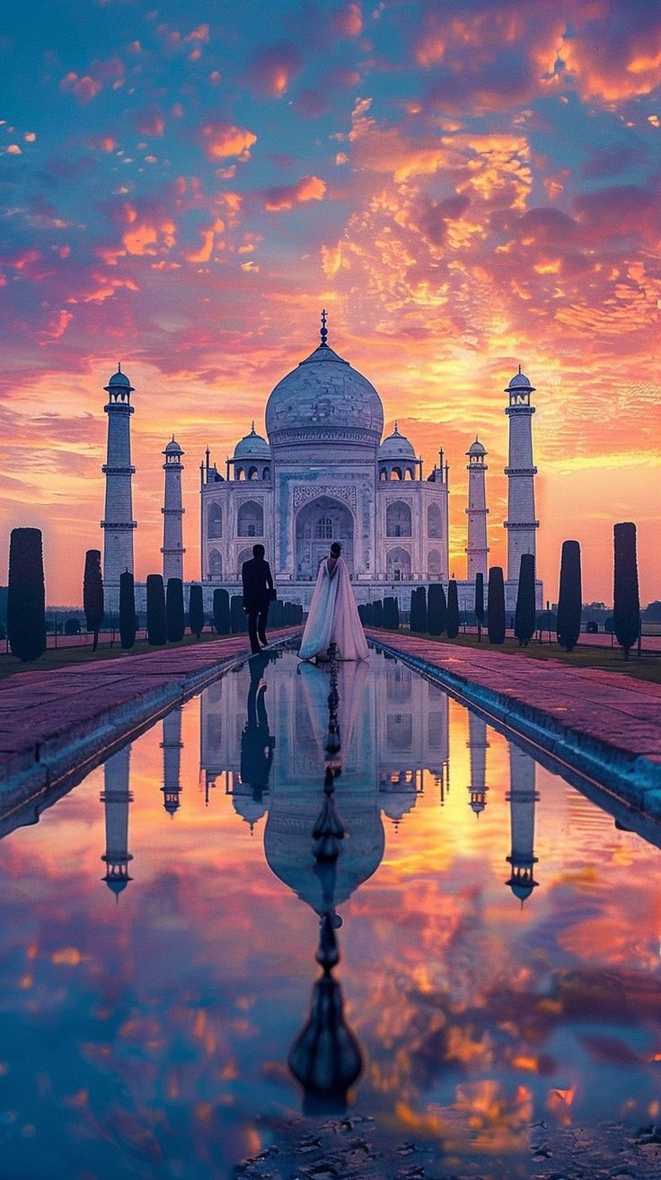 a bride and groom standing in front of the tajwa mosque at sunset, india