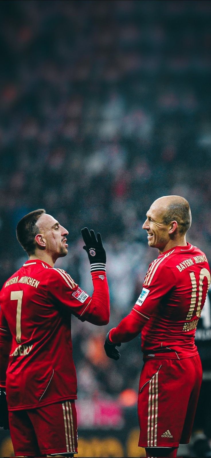 two men in red uniforms standing next to each other on a soccer field with their hands together