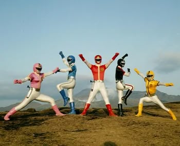 five people dressed in colorful costumes standing on top of a hill with their arms up