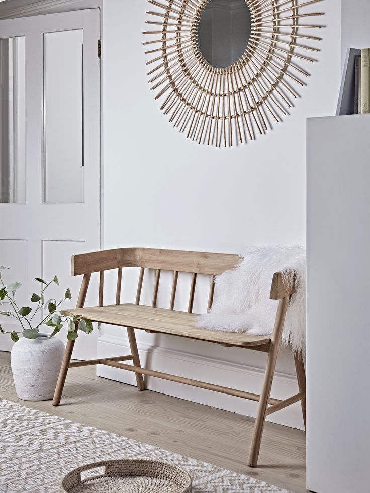 a wooden bench sitting in front of a mirror on the wall next to a potted plant