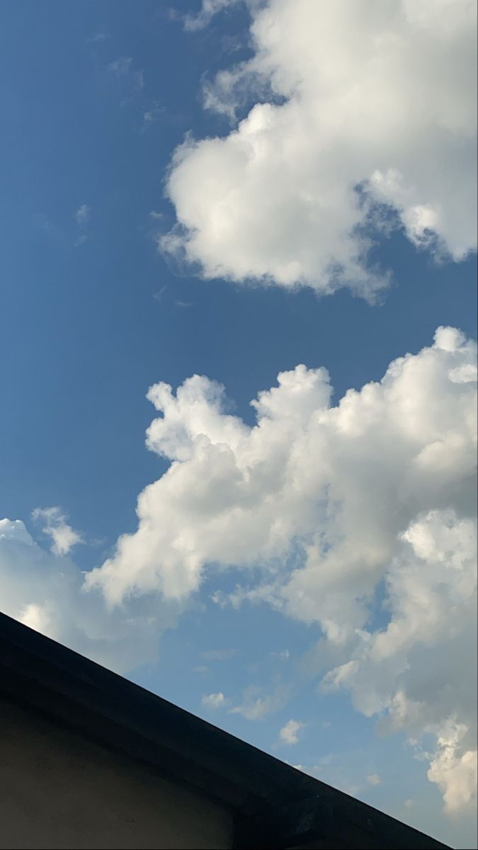 there is a clock on the top of a building with clouds in the sky behind it