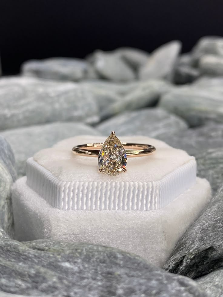 a yellow diamond ring sitting on top of a white box