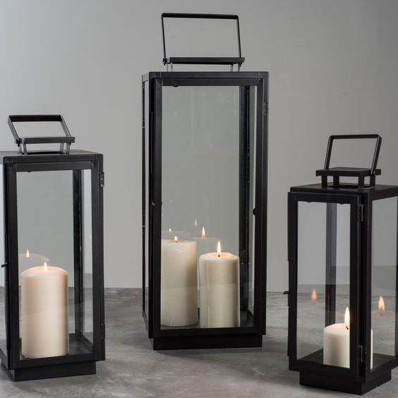 three black lanterns with lit candles in them