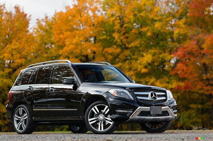 a black mercedes glk parked in front of trees with fall colors behind it and the words,