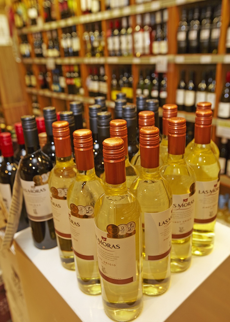 several bottles of wine are lined up on a shelf in a liquor store with other bottles behind them