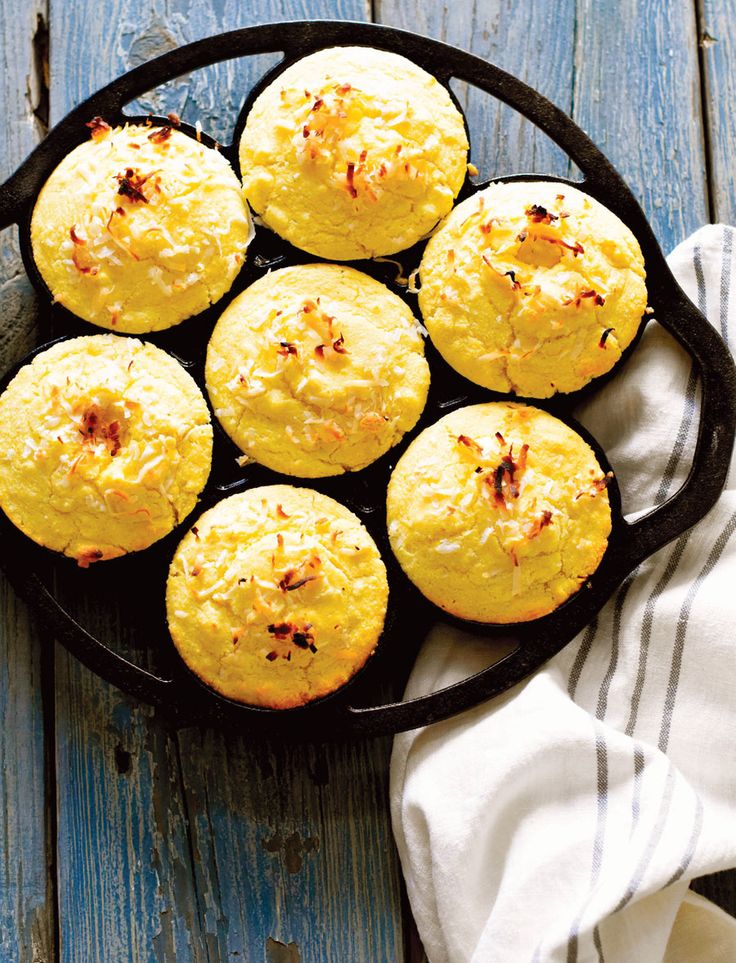 a pan filled with muffins sitting on top of a wooden table next to a white towel