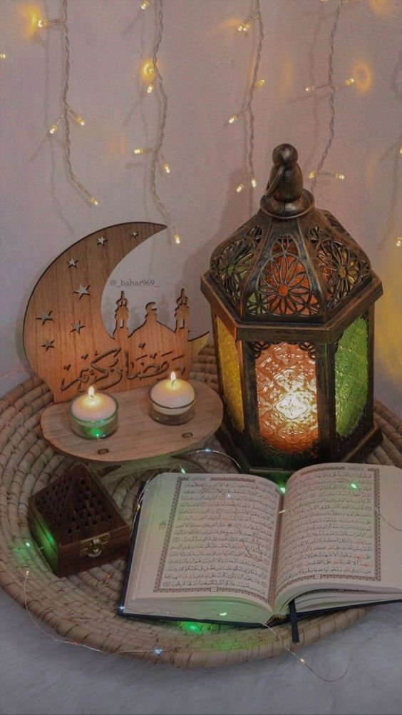 an open book sitting on top of a wicker basket next to two lit candles