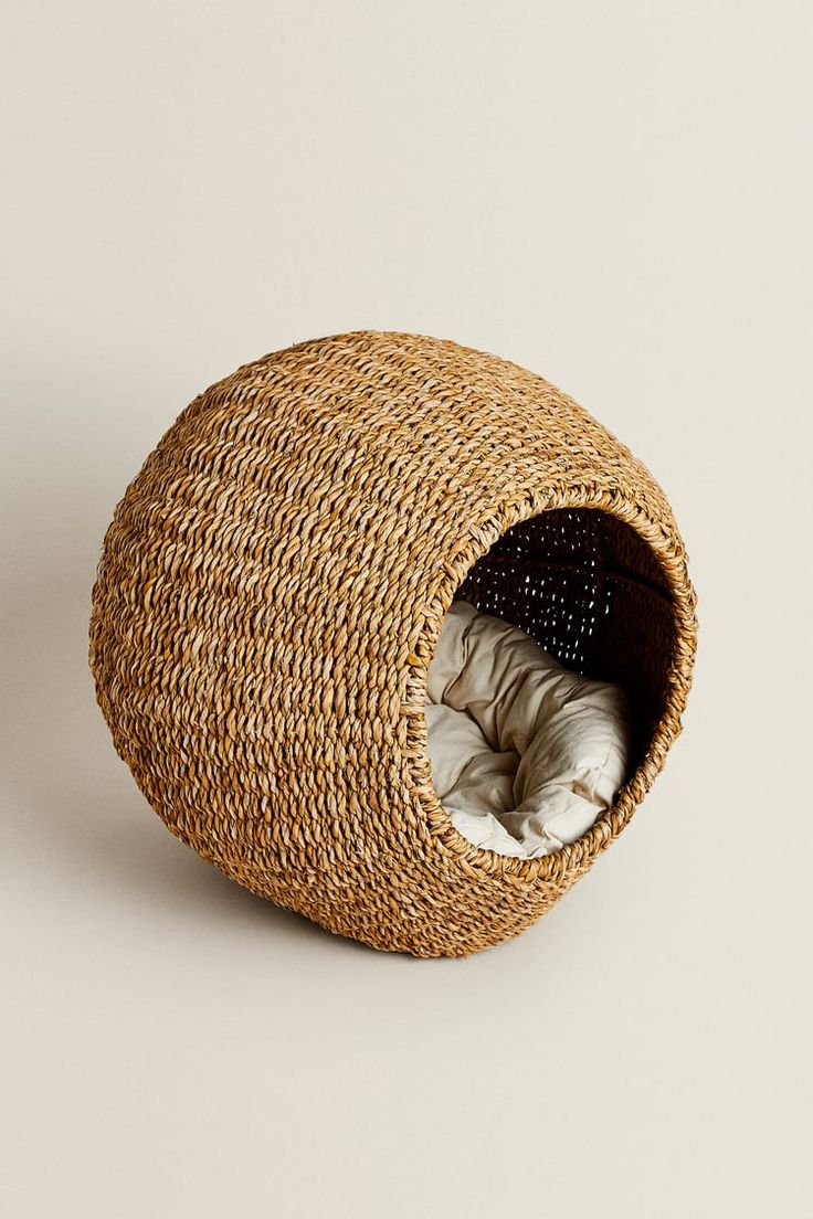 a woven basket with a white blanket in it on the floor next to a wall