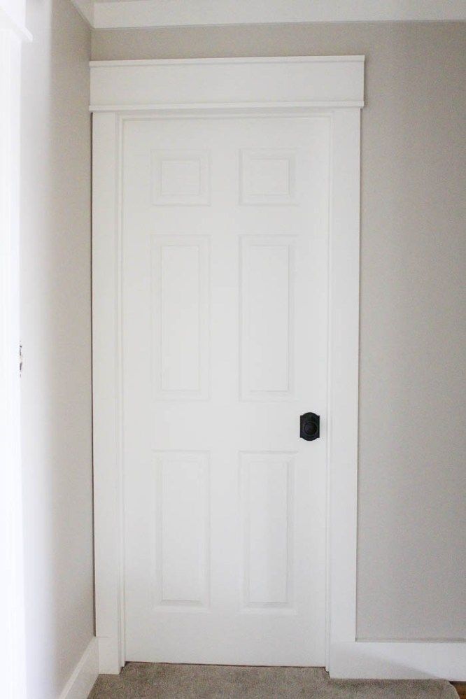 an empty room with a white door and carpet