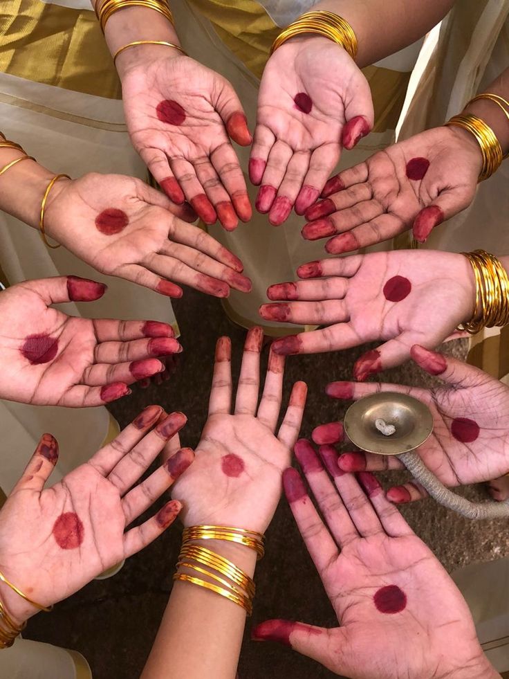 many hands are arranged in the shape of a circle with red spots on them and gold bracelets