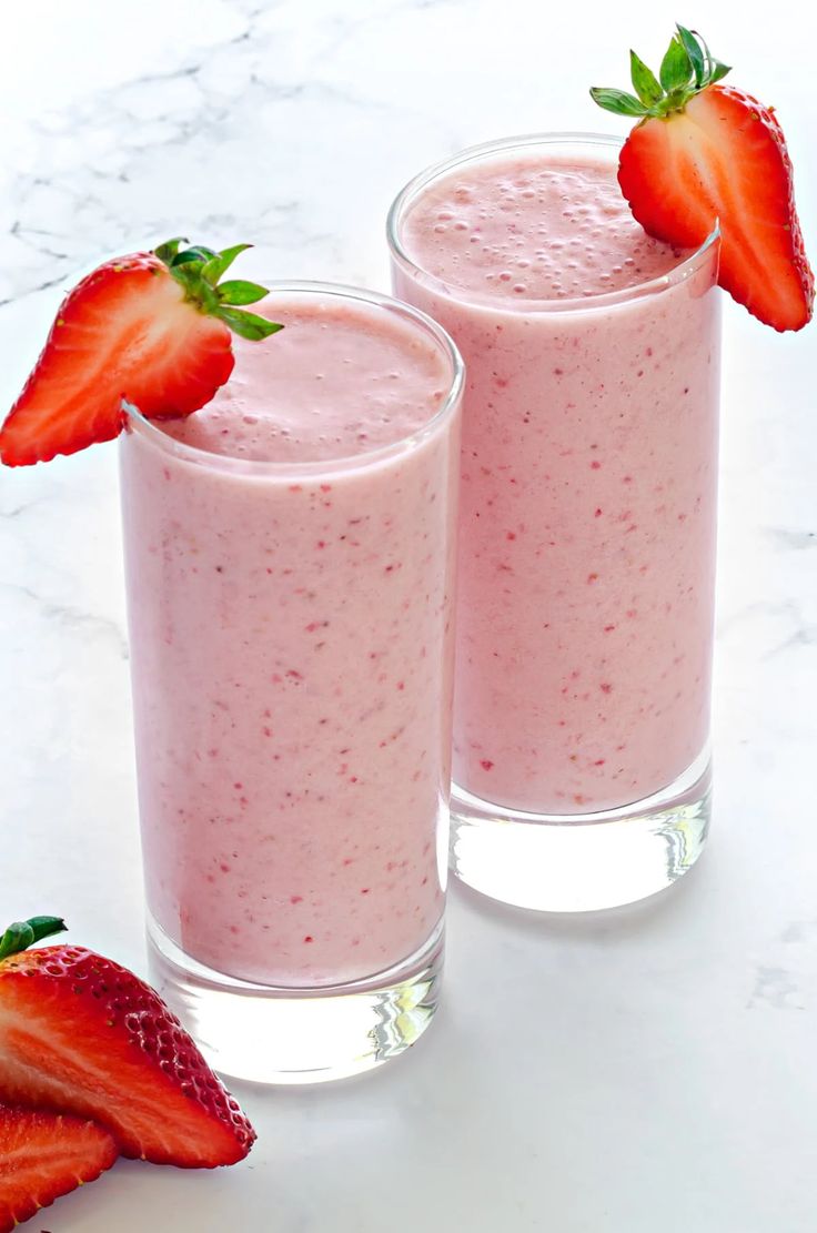 two glasses filled with smoothie and strawberries