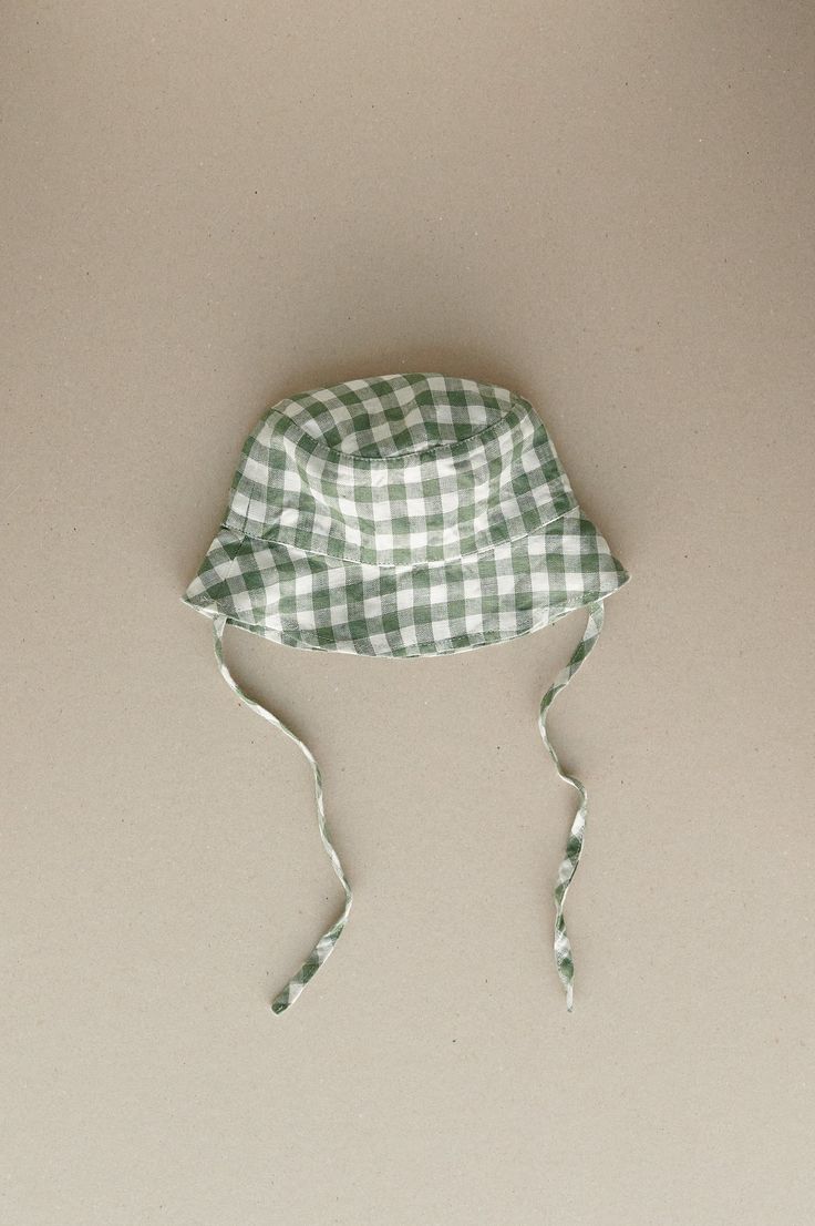 Product photos - green gingham. Our baby bucket hat will help to stay protected and keep it cute. Tailored to shade the face and ears along with side ties to keep the hat secure. A classy and comfortable choice for any forecast. Lightweight, cozy and charming. This baby bucket hat is designed to be comfortably loose-fitting and allow for growth as the baby grows. Casual Gingham Hats For Summer, Summer Plaid Bucket Hat, Summer Gingham Hat With Curved Brim, Plaid Curved Brim Hat For Beach, Plaid Curved Brim Hat For The Beach, Plaid Hats For Summer Beach, Plaid Summer Beach Hat, Summer Plaid Brimmed Hat, Adjustable Plaid Hats For Beach