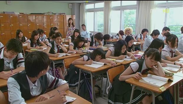 many students are sitting at their desks in the classroom and one student is taking notes