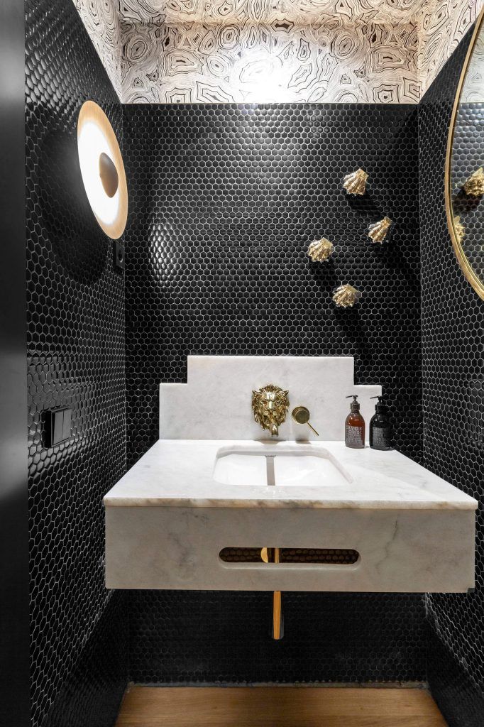 a white sink sitting under a mirror next to a wall mounted faucet in a bathroom