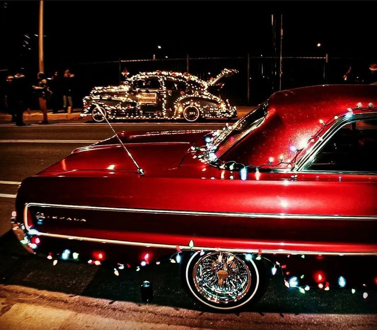 an old red car is decorated with christmas lights