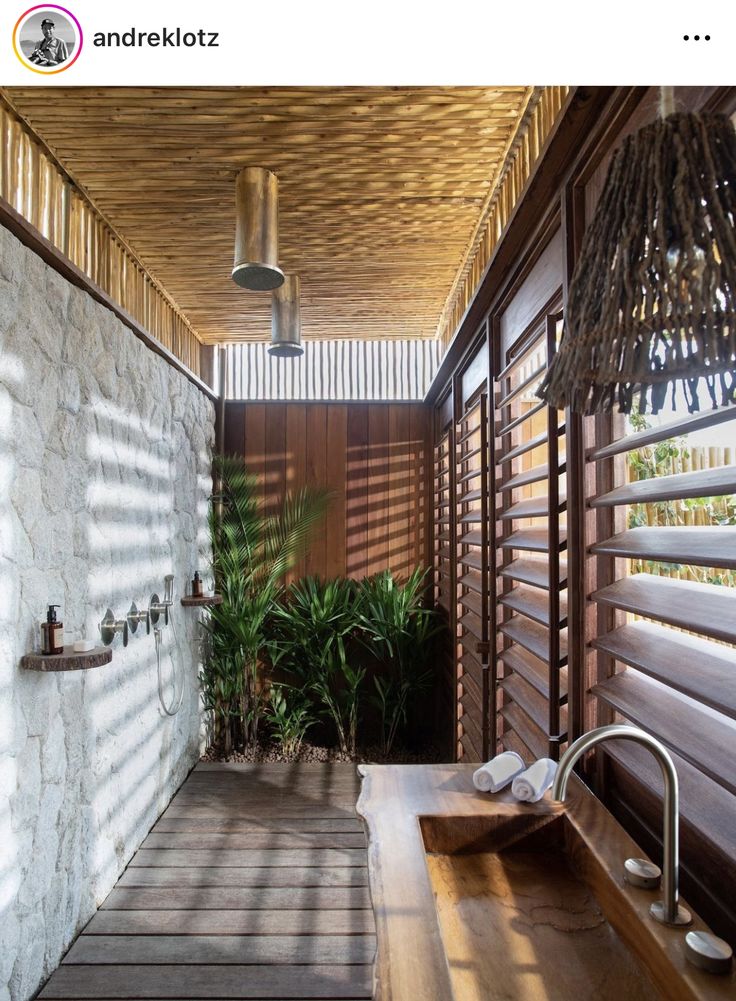 an outdoor bathroom with wooden flooring and walls, along with large window shades on the side