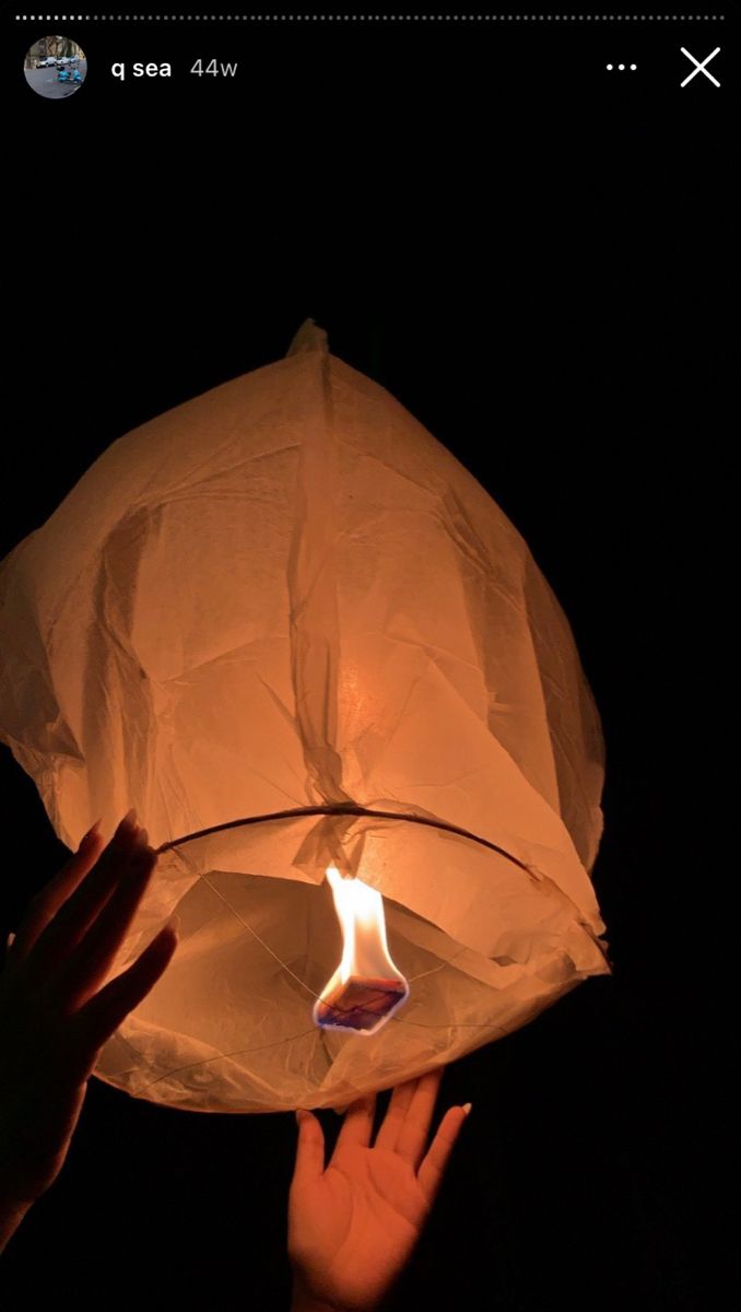 someone holding a paper lantern in their hand with the light on it's side