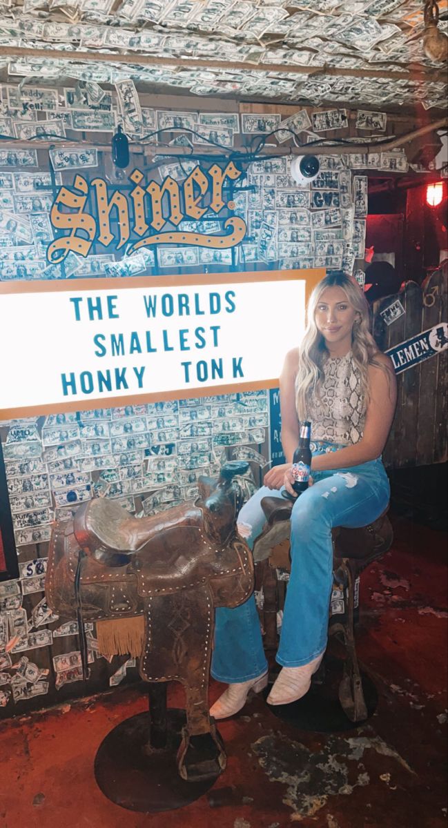 a woman sitting on top of a wooden horse next to a sign that says shiner