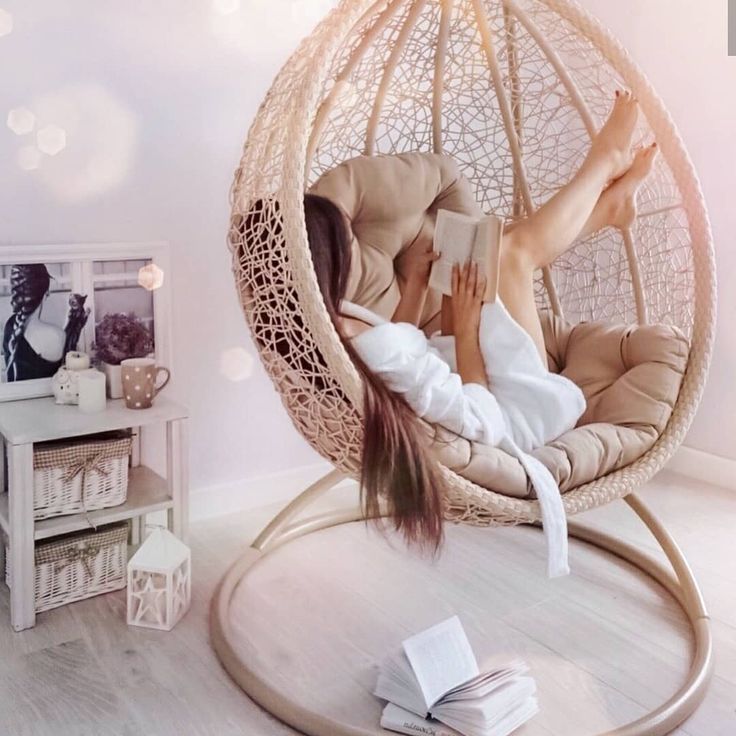 a woman laying in a hammock chair reading a book