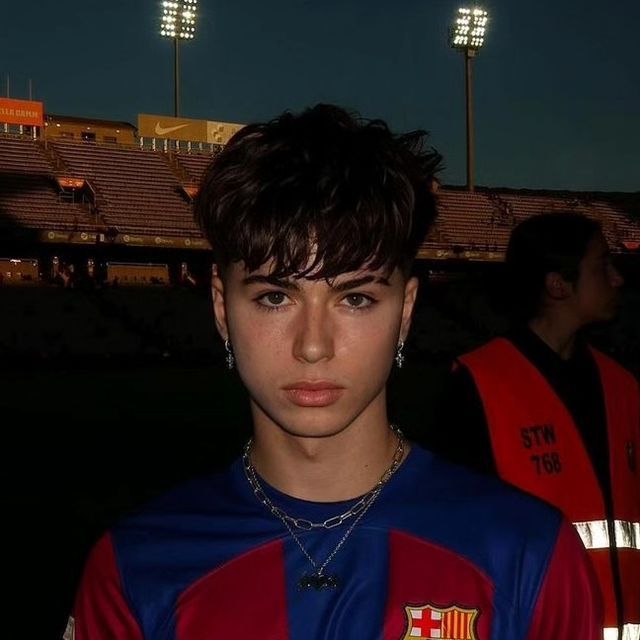 a young man wearing a red and blue uniform in front of an empty stadium at night