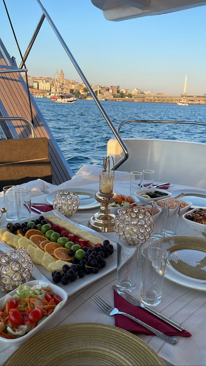 a table filled with plates and glasses on top of a boat near the water's edge