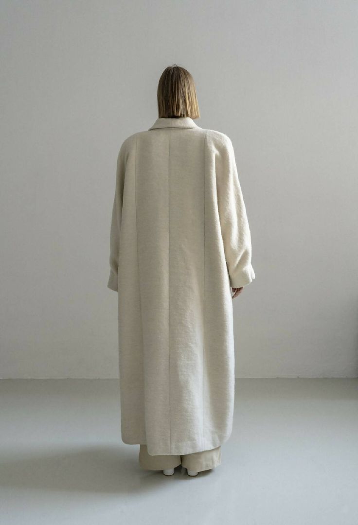 The Kosiv Cream Coat is a relaxed fit, long length coat, crafted from luxurious wool and hemp blend fabric traditionally handmade woven in Ukraine. Soft and compact to touch, this double breasted style features pleated oversize sleeves. This timeless piece is perfect for layering in the cooler seasons and will elevate any daytime or evening outfit. Lined.Composition 60% wool, 40% hempLining: 100% viscoseTrimming: 100% metalThis item is made of a blend of 40% hemp and 60% wool and it´s undyed.Hem Elegant Oversized Beige Wool Coat, Elegant Long Oversized Wool Coat, Beige Oversized Wool Coat With Lapel Collar, Oversized Long Classic Wool Coat, Classic Long Oversized Wool Coat, Classic Oversized Long Wool Coat, Oversized Single-breasted Wool Coat, Oversized Beige Wool Coat For Spring, Oversized Beige Wool Sweater Coat