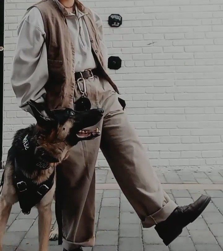 a man is walking his dog down the street in front of a white brick wall