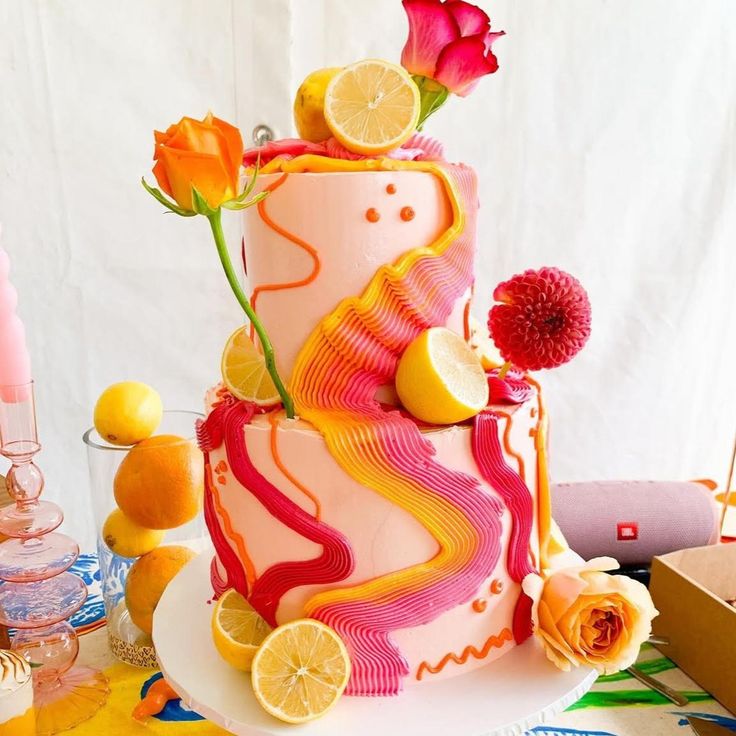 a three tiered cake decorated with lemons, oranges and flowers on a table