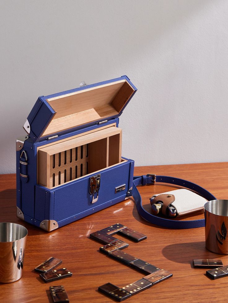 a blue suitcase sitting on top of a wooden table next to cups and spoons