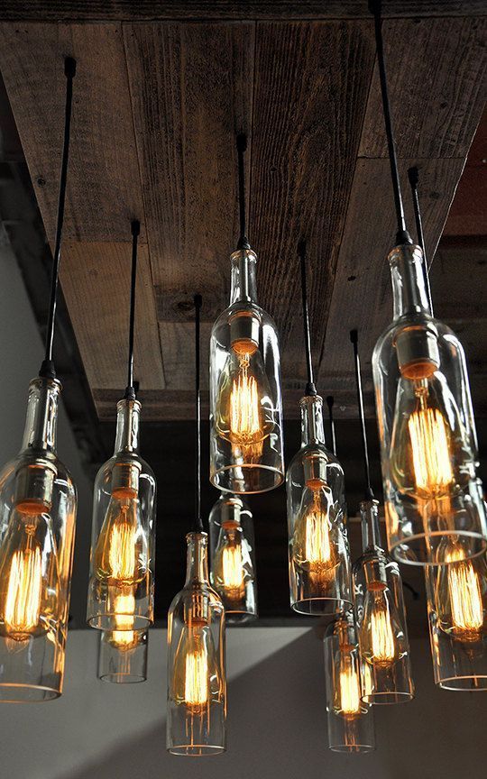 a chandelier made out of glass bottles and hanging from the ceiling with lights