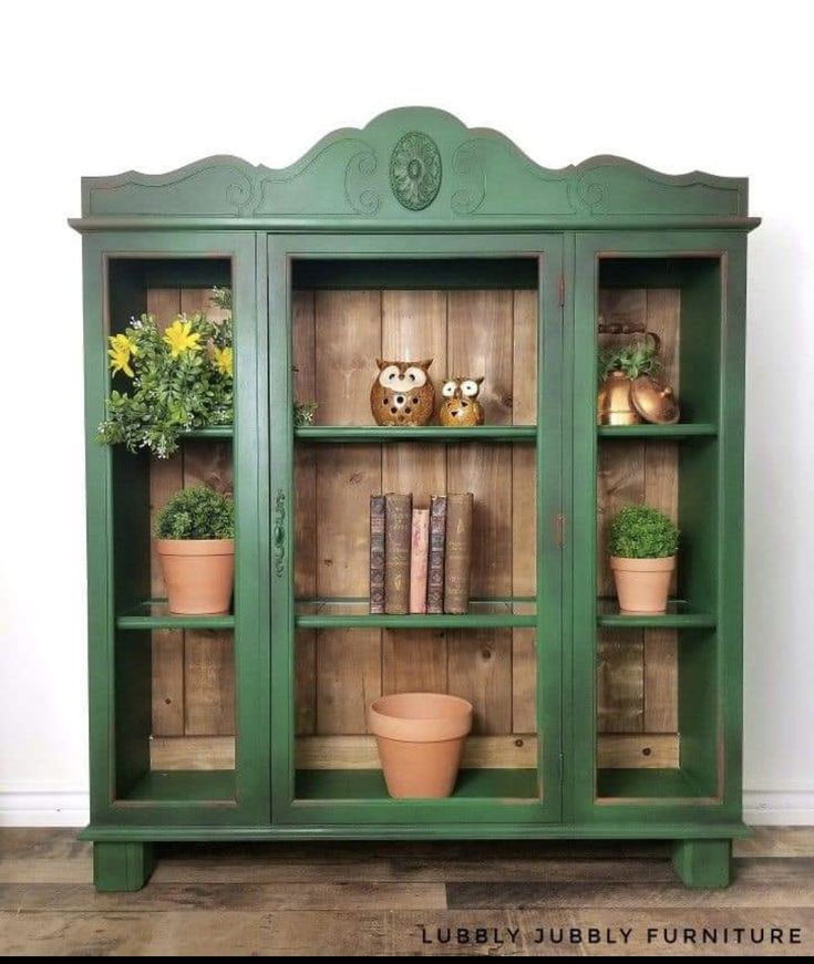 a green bookcase with potted plants on top