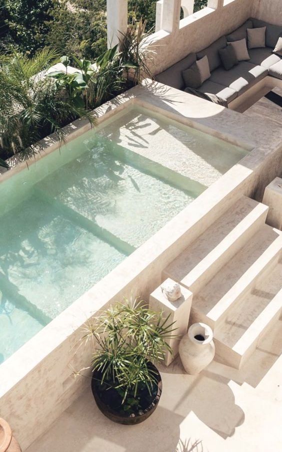 an outdoor swimming pool with lounge chairs and potted plants next to it, surrounded by greenery