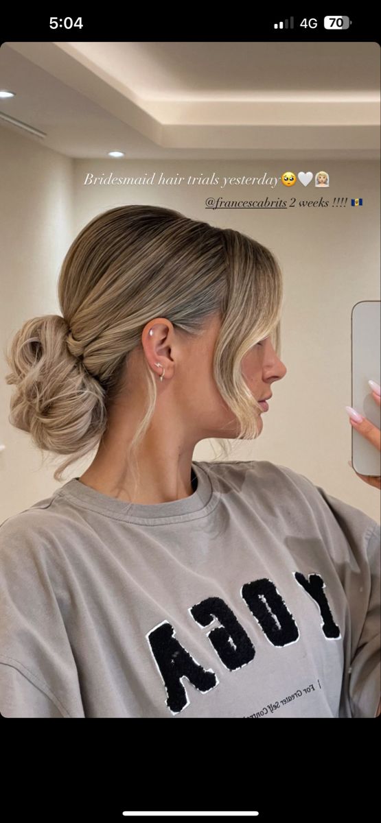 a woman with blonde hair is looking at her cell phone while wearing a grey sweatshirt