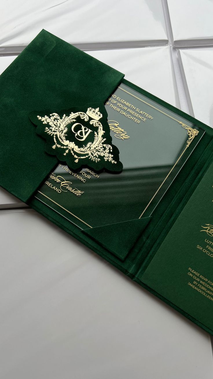 a green and gold wedding card with a monogrammed pocket