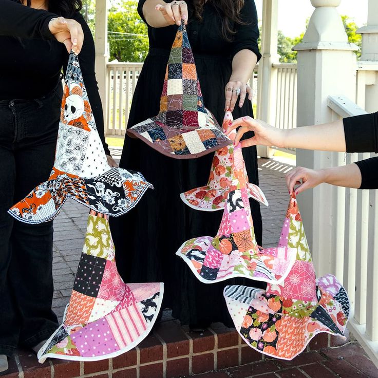 three women are holding up colorful umbrellas in front of a white picketed fence